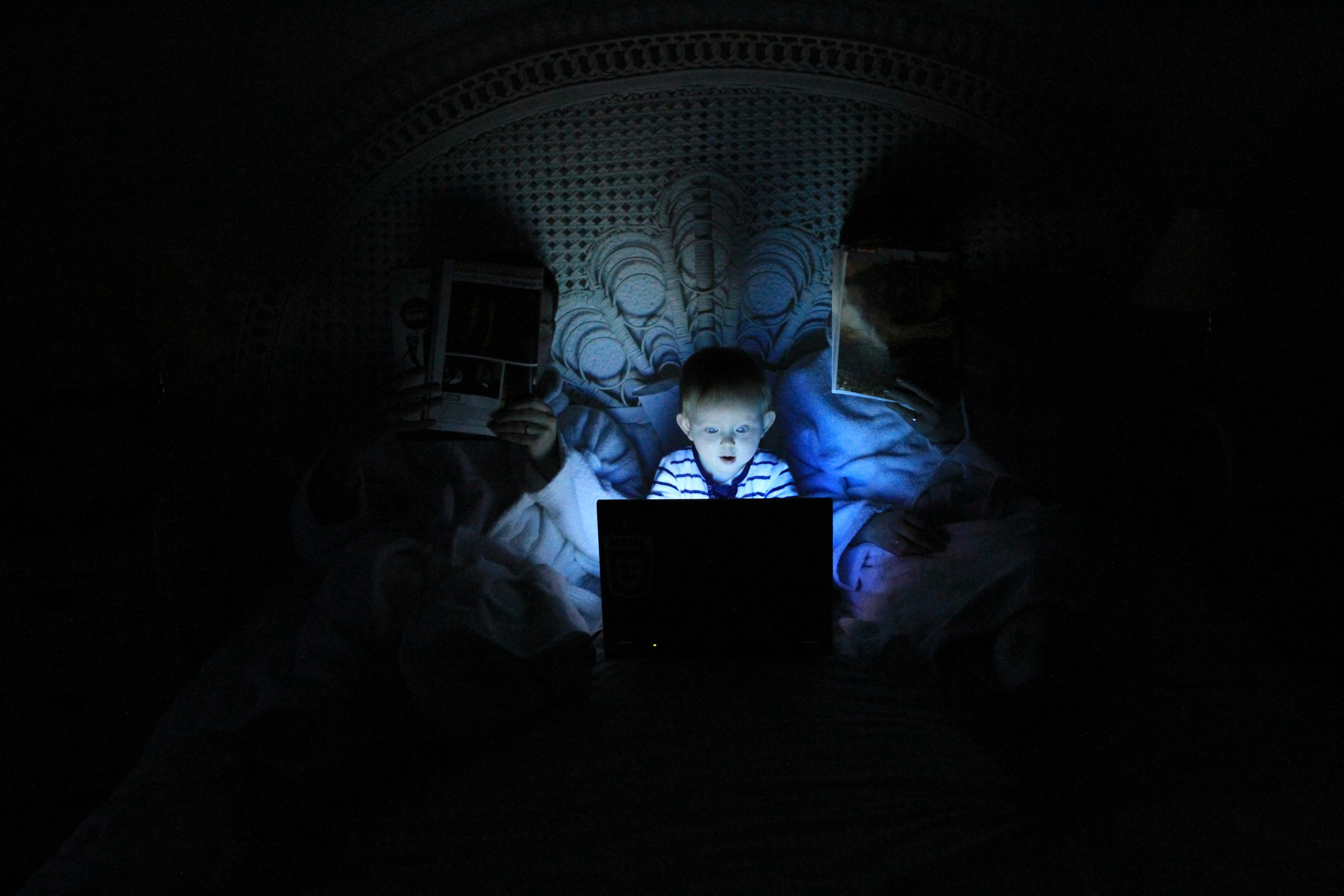 A child using a laptop in a darkened room